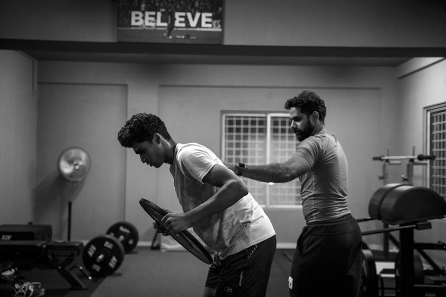 Coach cueing an athlete's back position to relieve back pain and improve movement, black and white