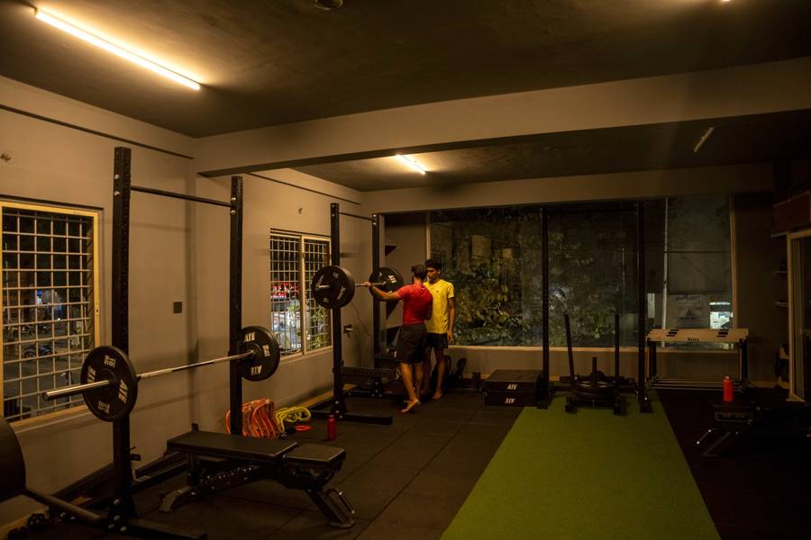 Squat racks, barbells and turf lane in the Kasturi Nagar strength training studio