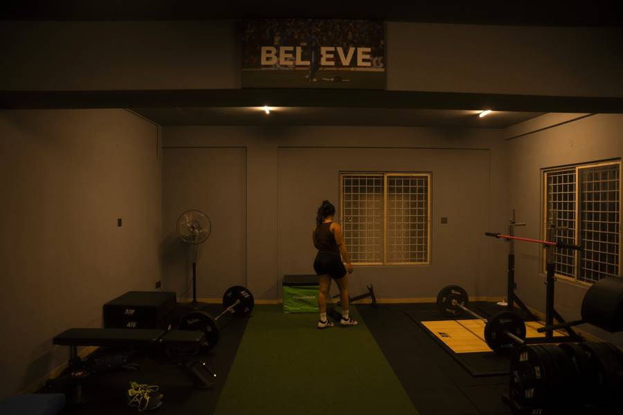 Athlete training alone in the strength and rehab studio under the BELIEVE sign, Kasturi Nagar