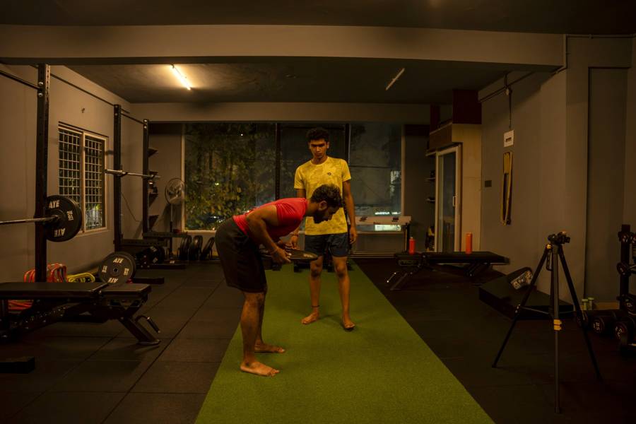 Coach demonstrating a hip hinge with a weight plate, a key drill for lower back pain rehab