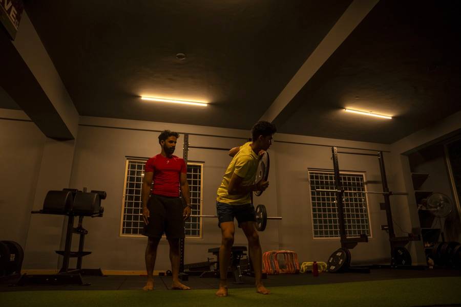 Coach assessing an athlete's rotational movement during a strength and rehab session