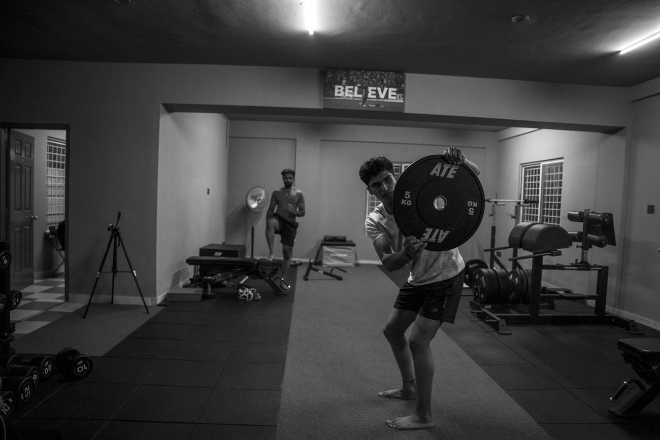 Athlete driving a weight plate overhead in an explosive power drill, sports performance training in Bengaluru