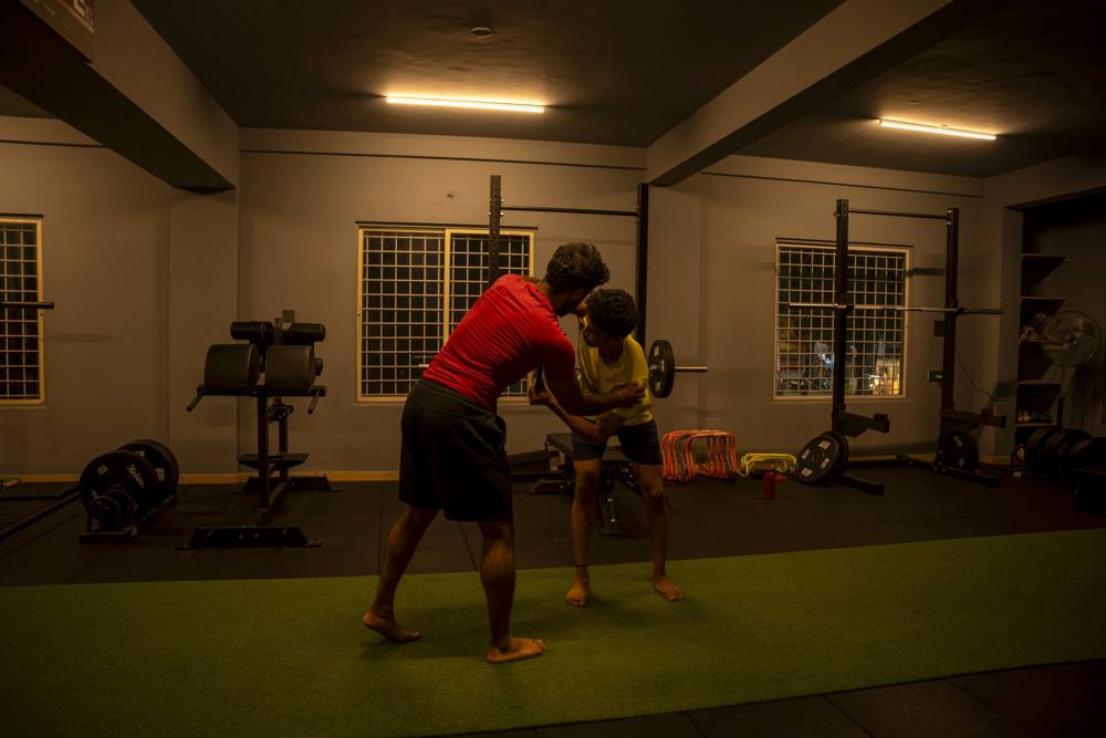 Coach guiding an athlete's posture by hand during a pain and injury rehab session