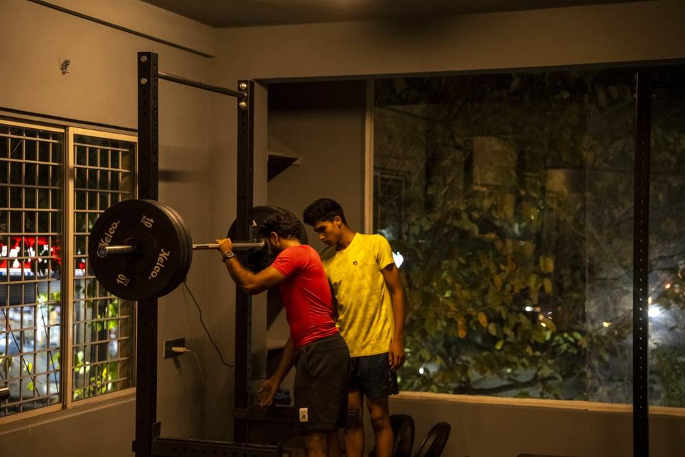Strength and conditioning coach at the squat rack teaching an athlete safe barbell technique